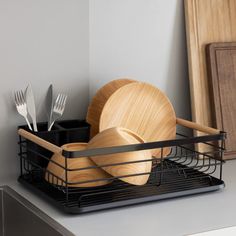 a black dish rack with wooden utensils and plates in it on a counter