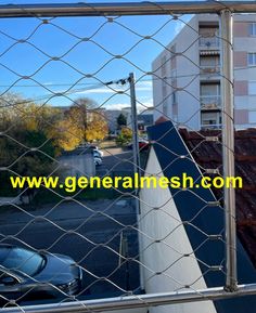 the view from behind a chain link fence looking down at a parking lot and buildings