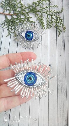 someone is holding two brooches made out of glass beads and bead wire