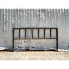 a metal bench sitting in front of a wall