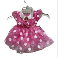 a pink and white polka dot dress hanging on a clothes line with a tag attached to it