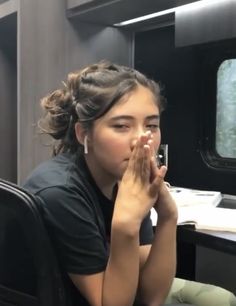 a woman sitting at a desk with her hand on her face