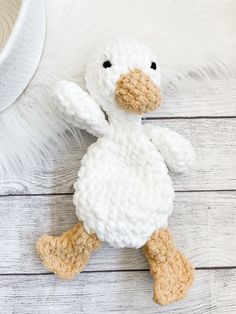 a crocheted white duck laying on top of a wooden floor