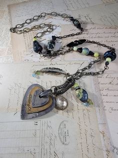 "Art Assemblage Necklace: I created the long necklace by building it around a Mixed Metal heart that says \"gorgeous strength, and spirit\" with some odd charms from salvaged jewelry.  There are stone and Czech glass beads, and brass feather charms, chips, chrystal charm and patinaed brass chains. The eclectic mix is very organic, natural and endearing. It measures 33 inches long with a 4 inch pendant that is adjustable with a lobster clasp." Unique Metal Jewelry With Heart Charm, Unique Metal Necklace With Heart Charm, Artisan Silver Necklace With Heart Charm, Bohemian Heart-shaped Metal Necklaces, Bohemian Metal Heart Pendant Necklace, Bohemian Metal Jewelry With Heart Charm, Metal Heart Pendant Necklace With Soldered Details, Bohemian Heart-shaped Metal Charm Necklace, One-of-a-kind Heart Shaped Spiritual Jewelry