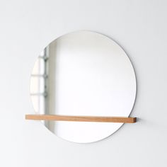 a round mirror hanging on the wall next to a wooden shelf