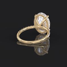 a yellow gold ring with an oval cut diamond in the center, surrounded by smaller round diamonds