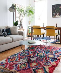 a living room filled with furniture and a colorful rug on top of a hard wood floor