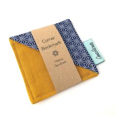 the corner bookmark is made out of yellow fabric and has a blue flower design on it