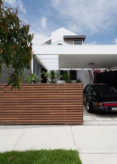 a car is parked in front of a house with wooden slats on the fence