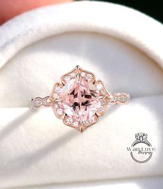 a pink diamond ring sitting on top of a white cloth