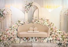 a couch sitting on top of a lush green field covered in white and pink flowers