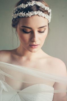 a woman wearing a bridal headpiece with flowers on it's side and her eyes closed