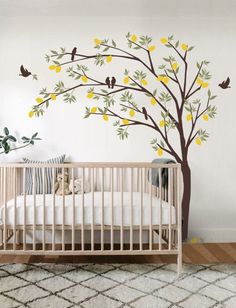 a baby's room with a tree painted on the wall and birds flying around