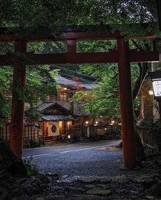 an entrance to a japanese style house in the woods at night with lanterns lit up