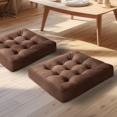 two brown foot stools sitting on top of a hard wood floor next to a coffee table