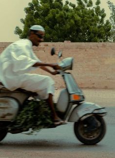 a man riding on the back of a moped