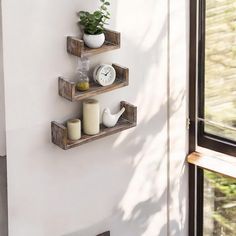 three wooden shelves with candles and plants on them