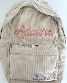 a backpack with embroidered name and flowers on it