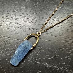 One of our brand new OCEAN KYANITES (named for their ocean-like blues!) is suspended from our new, tiny GOLD bail with 14K Gold wire wraps and 14K Gold Chain! This combo of the bright gold and deep blue looks so great together! For this piece, we switched it up and had our thick, 24K Gold electroplating added to our brass bail to create a lovely and durable luster. Ocean Blue kyanite helps open psychic ability, enhances telepathic communication and assists in lucid dreaming. It has a potent abil Everyday Gold Sapphire Jewelry, Everyday Hand Wrapped Blue Jewelry, Blue Gemstone Jewelry In Recycled Gold, Blue 14k Gold-filled Wire Wrapped Jewelry, Blue 14k Gold Filled Wire Wrapped Jewelry, Blue Minimalist Brass Jewelry, Blue Hand Forged Jewelry For Healing, Minimalist Blue Brass Jewelry, High Frequency Energy