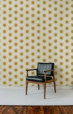 a chair sitting in front of a wall with gold circles on it's back