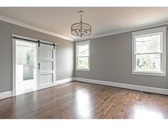 an empty living room with hard wood floors and white trim on the doors, windows, and french doors