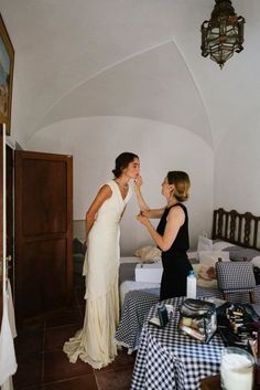 two women standing next to each other near a bed