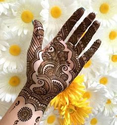 the hand is decorated with henna on it and has yellow flowers in front of it