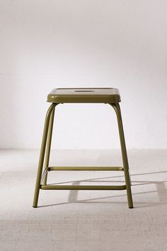 a green stool sitting on top of a white floor in front of a white wall