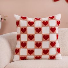 a red and white checkerboard pillow on a couch with hearts hanging from the back