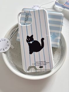 a phone case with a black cat on it sitting on top of a white plate