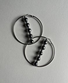 Truly an eye-catching accessory, this unique pair of dangle hoop earrings is made to bring your look full circle. Thanks to the earring material being Stainless Steel, you can wear these cuties in and out of the water without worrying about them rusting. With that said, be cautious about getting Hematite into the water for extended periods of time. Handmade in Houston & produced in small batches with a lot of love and attention to detail. Only made in drops; get your pair while supplies last.  All earrings get packaged into individual decorated boxes, perfect for gift giving or keepsake. *FREE SHIPPING ON ALL DOMESTIC ORDERS* Dimensions: 2.75-inch Hoops (70mm) Materials: Stainless Steel & Hematite xoxo KMBR Decorated Boxes, Skeleton Earrings, Into The Water, Ghost Earrings, Dangle Hoop Earrings, Cross Earrings, Sterling Silver Hoop Earrings, Full Circle, Sterling Silver Hoops