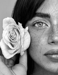 a woman with freckled skin holds a rose in her hand to her face