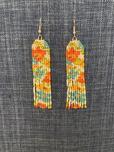 These may be one of my favorites!  These unique floral and fringe showcase coral, teal, and yellow against a white background.  The floral motif runs top to bottom.  You won't find another pair like these.  The earrings are made with top quality beads, materials, and sterling silver hooks.  Each bead is attached by hand.  The earrings are light weight and measure 3.25 in long and 0.75 in wide.  The item in picture is the item you will receive.  Earrings will arrive on an earring card sealed for Bohemian Tassel Earrings With Fringe For Spring, Multicolor Beaded Drop Earrings For Spring, Spring Bohemian Beaded Dangling Earrings, Spring Multicolor Beaded Drop Earrings, Bohemian Fringe Earrings For Spring, Bohemian White Beaded Earrings For Spring, Spring Bohemian Fringe Earrings, Spring Multicolor Beaded Earrings, Spring Bohemian Tassel Earrings