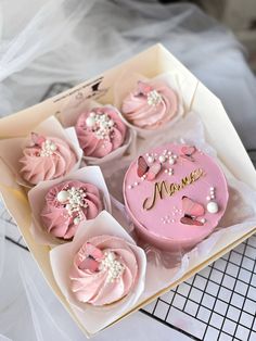 a box filled with pink cupcakes covered in frosting