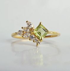 a yellow gold ring with an emerald and white diamond set in the middle, on a plain surface