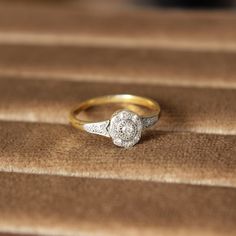 a diamond ring sitting on top of a brown velvet covered surface with a black object in the background