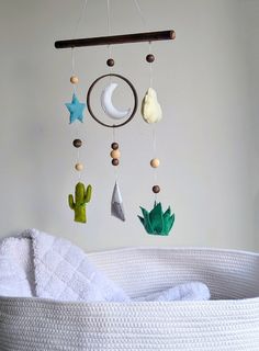 a baby crib with a mobile hanging from it's side and cactus decorations