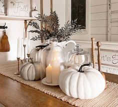 some white pumpkins and candles on a table