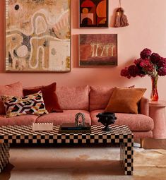 a living room with pink walls and art hanging on the wall, including a checkerboard coffee table