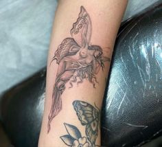 a woman's arm with a butterfly and flower tattoo design on the left forearm