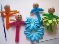 four small dolls are sitting on top of a white surface next to crocheted flowers