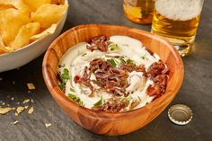 a wooden bowl filled with food next to some chips