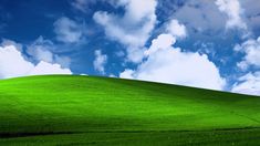 a green field under a blue sky with clouds