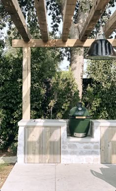 an outdoor bbq grill under a pergolated roof with two lights on it