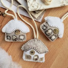 three ornaments are sitting on the floor next to some fabric and buttons, one is white