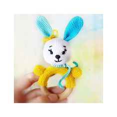 a hand holding a crocheted stuffed animal in the shape of a bunny with blue ears