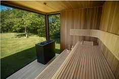 an empty sauna in the middle of a grassy area next to a large window