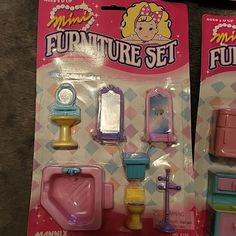 two toy furniture sets in plastic packaging on the floor, one has a sink and toilet