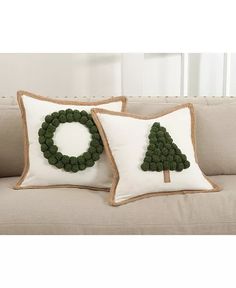 two pillows on a couch decorated with christmas wreaths and green beads are sitting next to each other