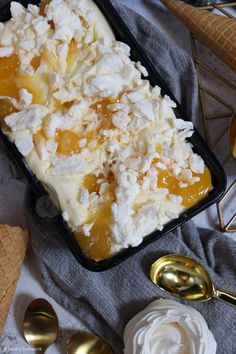 an ice cream sundae in a black tray with spoons and goldware around it